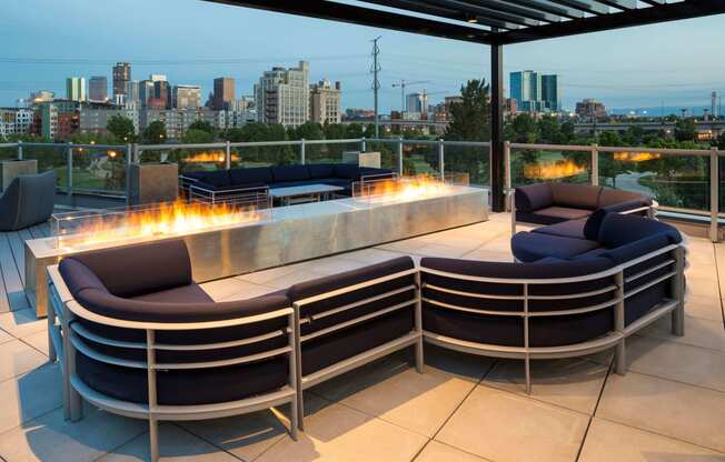 The stylish rooftop features a large outdoor fireplace, comfortable seating, and a pergola all looking out onto stunning skyline views.