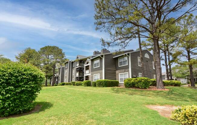 an apartment building on a grassy hill with trees in the background at Riverset Apartments in Mud Island, Memphis, TN