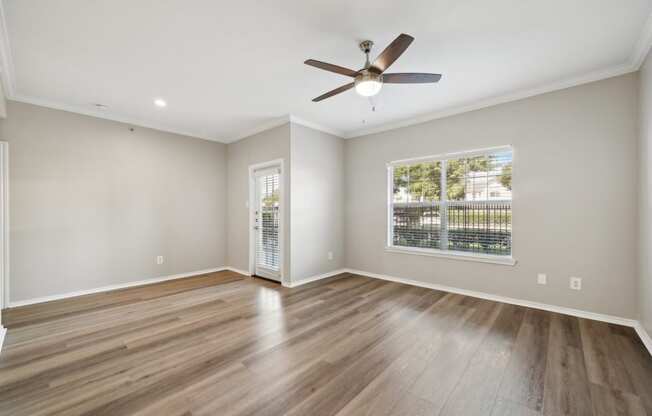 an empty living room with a ceiling fan and a window