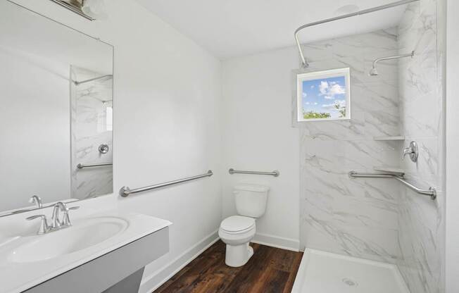 A bathroom with a white sink, toilet, and a shower with a marble wall.