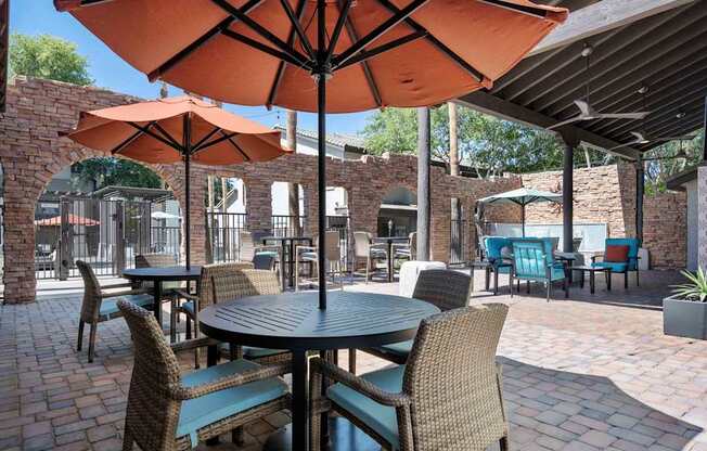 A patio with tables and chairs under umbrellas. at Lazo Apartment Homes, Arizona, 85225