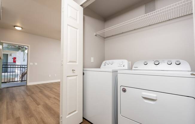 Apartments for Rent in 89147, Spring Valley, NV - Alicante - Bathroom with Hardwood-Style Floor, Bathtub, Wood-Tone Cabinet, Mirror, and Laundry Closet with Washer and Dryer