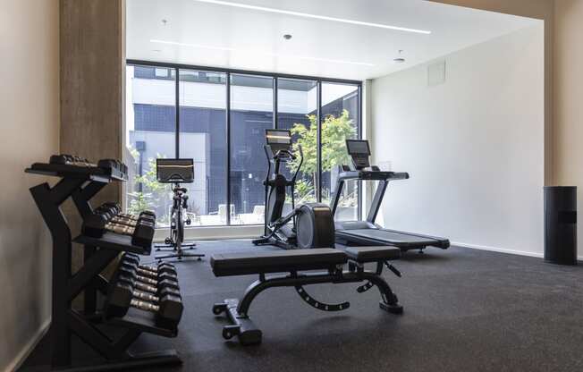 a gym with treadmills and other exercise equipment in front of a window at Analog PDX Apartments, Oregon 97227