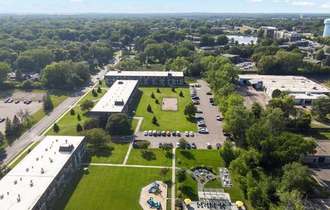 A large building complex with a green lawn and a pool in the foreground.