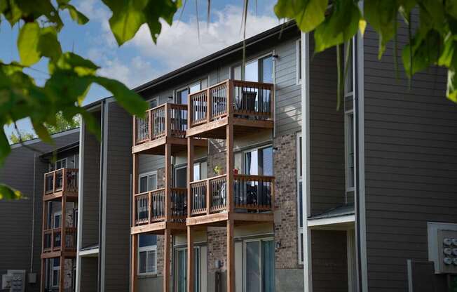 A building with a balcony and a tree in front of it.