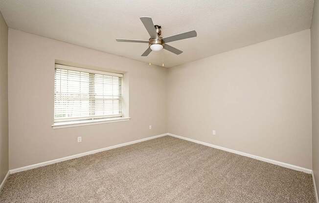 A room with a ceiling fan and a window with blinds.