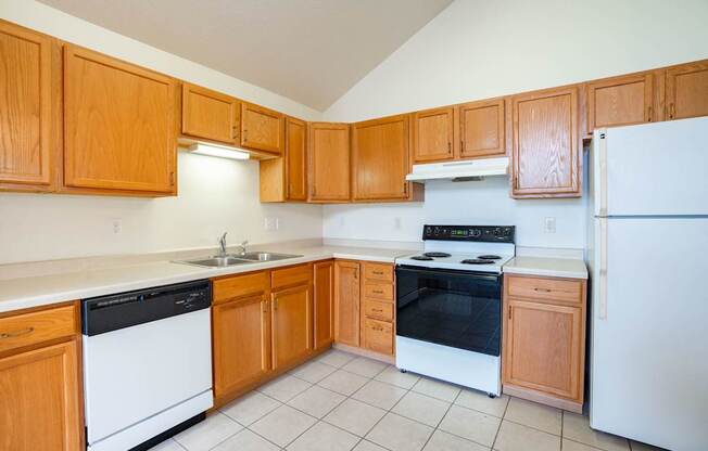 A kitchen with wooden cabinets and white appliances. Fargo, ND Summit Point Apartments