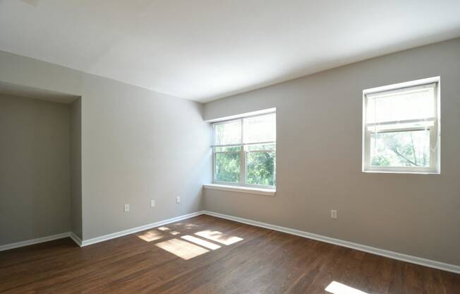 a bedroom with two windows and hardwood floors