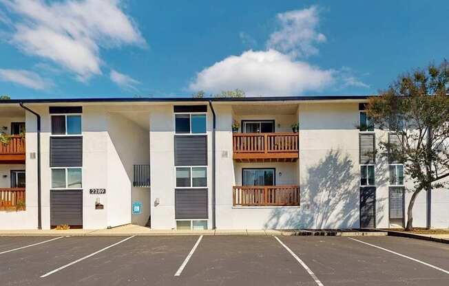 A modern apartment building with a parking lot in front.