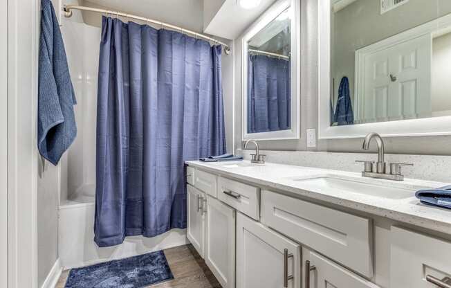 a bathroom with white cabinets and a blue shower curtain