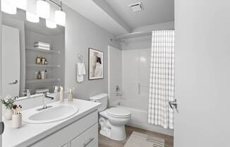A white bathroom with a sink, toilet, and shower.