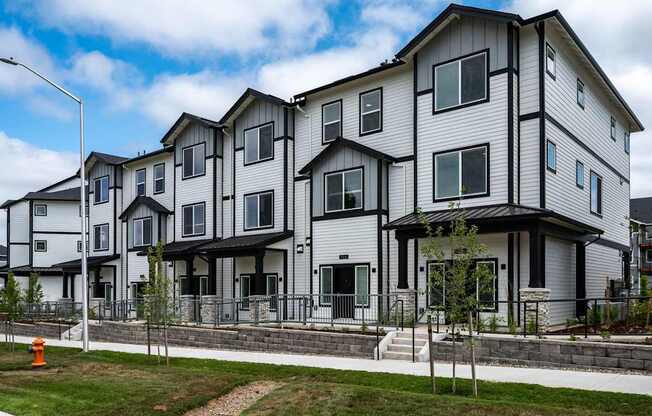A row of modern townhouses with a sidewalk and a street lamp.