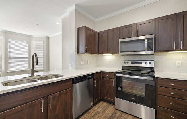 a kitchen with wooden cabinets and stainless steel appliances at The Verandah, Austin, TX