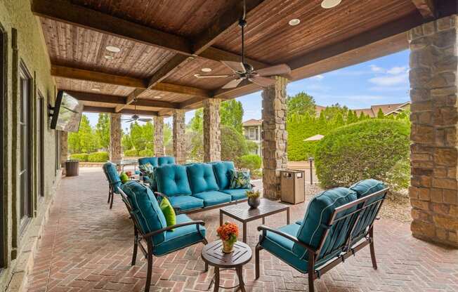 a covered patio with blue couches and chairs