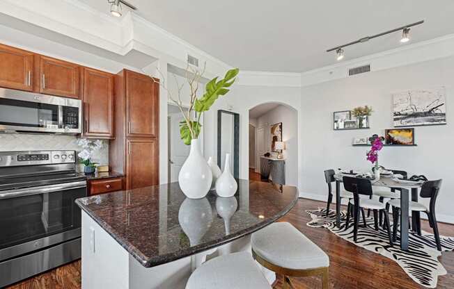 A kitchen with a black granite countertop and maple colored cabinets at Dominion Post Oak apartments in Houston, TX