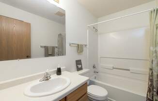 a bathroom with a sink and a toilet and a shower. Bismarck, ND Bradbury Apartments