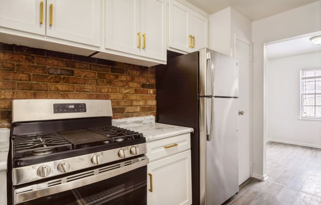 a kitchen with white cabinets and a brick wall