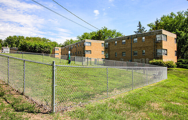 a fenced in grassy area with a brick building in the background