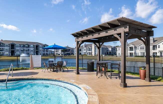 a pool with a wooden gazebo and patio furniture next to a pool