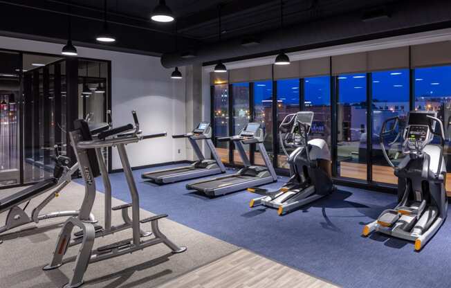 a workout room with treadmills and other exercise equipment at night at Maven on Broadway, Rochester, MN, 55904