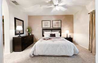 A bedroom with a large bed, a dresser, and a ceiling fan.