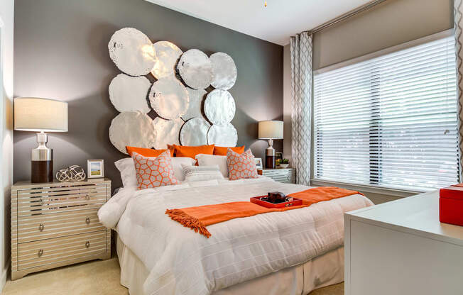 a bedroom with a white bed and orange pillows