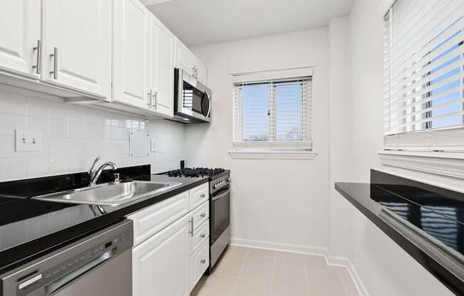 A kitchen with white cabinets and black countertops.