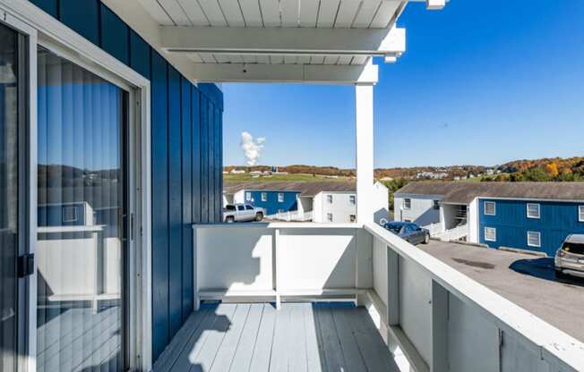 a covered balcony with a view of a parking lot and blue buildings