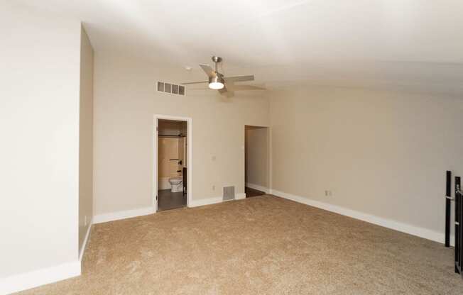 an empty living room with a ceiling fan