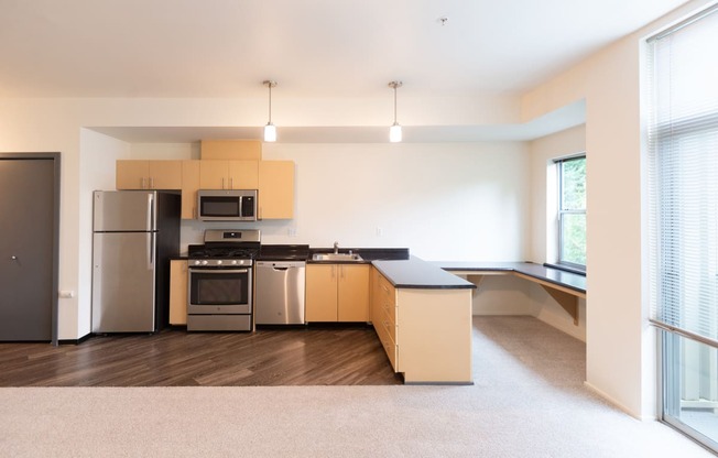 an empty kitchen with stainless steel appliances and wooden cabinets