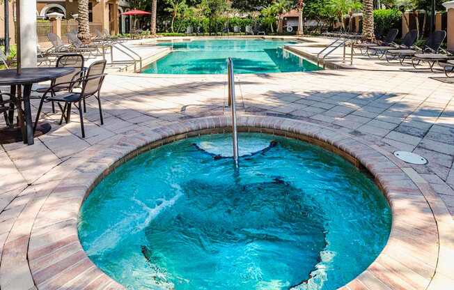 Bubbling spa beside the resort pool with lounge seating and palms