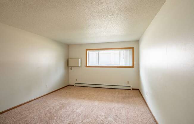 the living room of an empty house with a window. Fargo, ND Hawn Apartments