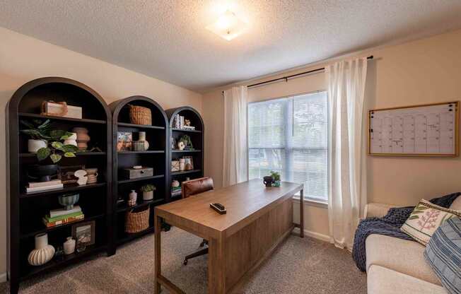 A room with a desk, two shelves, and a couch.
