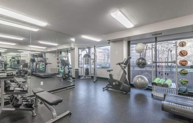 a gym with exercise equipment and weights on the floor and a mirrored wall