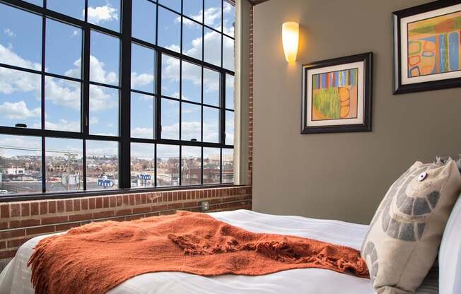 A bedroom with a large window overlooking a cityscape.