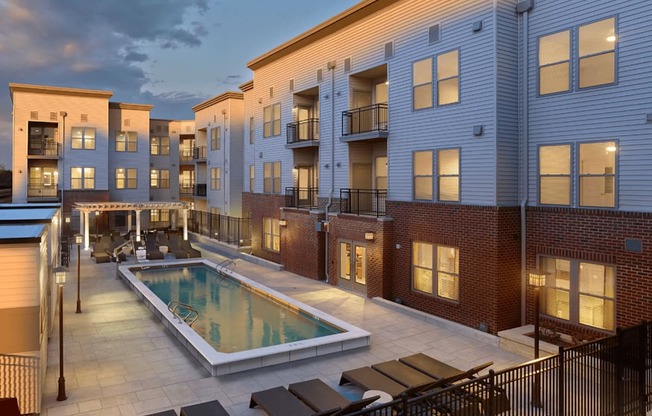 A pool surrounded by patio furniture and a black fence.