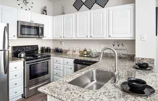 A kitchen with a granite countertop and stainless steel appliances.
