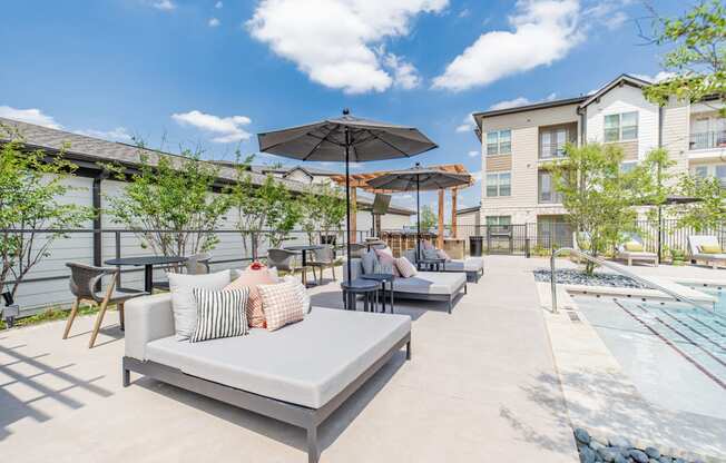 an outdoor patio with couches and umbrellas and a pool