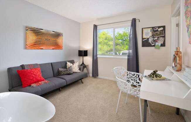 a living room with a couch and a desk and a window