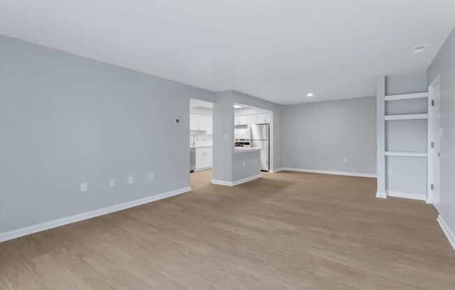 a living room and kitchen with a wood floor and grey walls