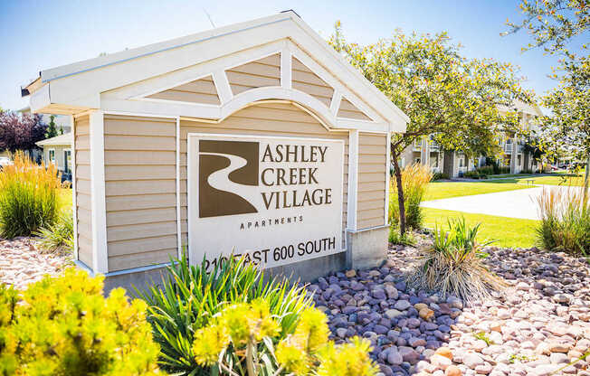A sign for Ashley Creek Village Apartments is displayed in front of a landscaped area.