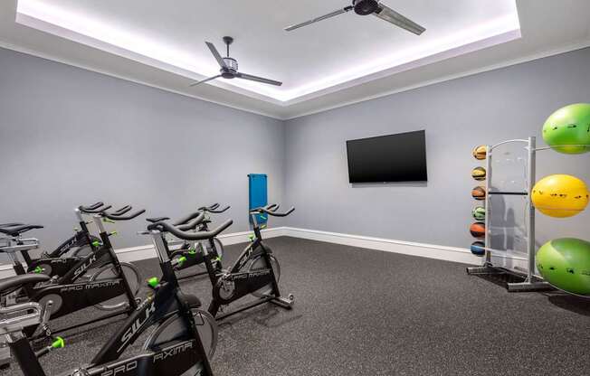 A room with exercise bikes and a fan.