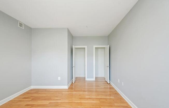 a bedroom with grey walls and a hardwood floor