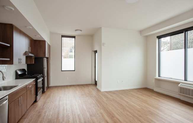 an empty living room and kitchen with wood flooring and a window