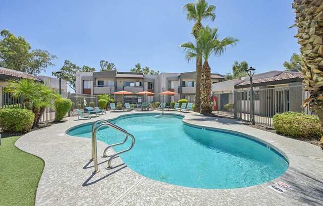 A large swimming pool surrounded by a concrete patio and a metal fence.
