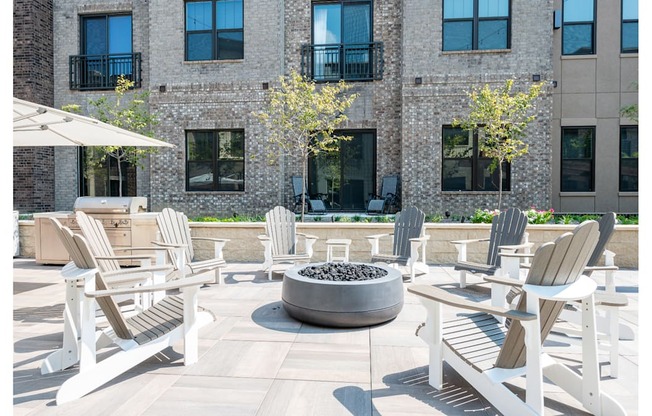 A patio with white chairs and a fire pit.