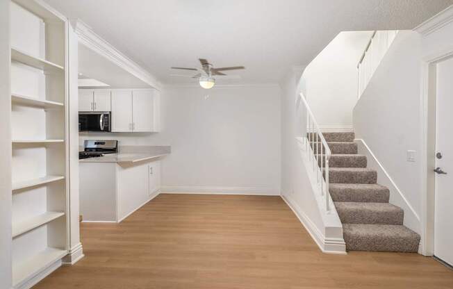 A white kitchen and dining space with a staircase leading to the second floor.