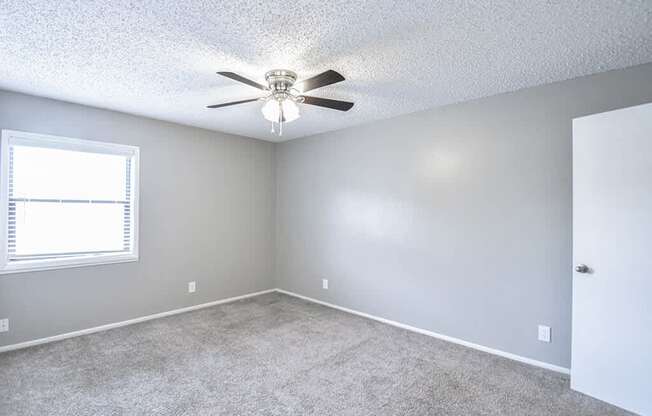 an empty room with a ceiling fan and a window