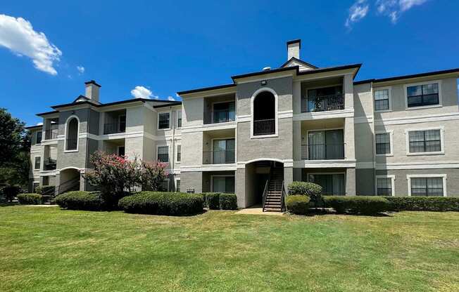 A three-story apartment building with attached garages at Saxony at Chase Oaks Apartments in Dallas, TX, offering modern conveniences in a beautifully maintained setting.