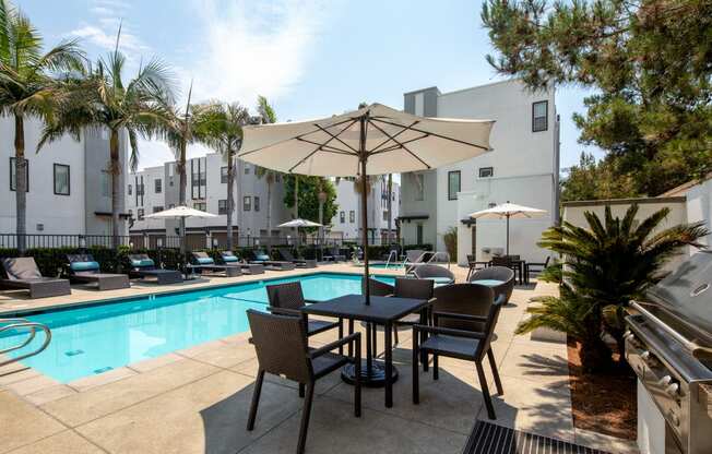 A patio with a table and chairs is surrounded by palm trees.